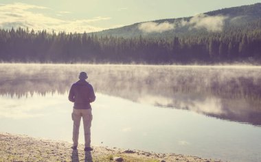 Bir adam sakin gölün yanında dinleniyor. Rahatlama tatili