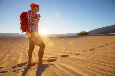 Kum çölünde bir yürüyüşçü. Gün doğumu zamanı.