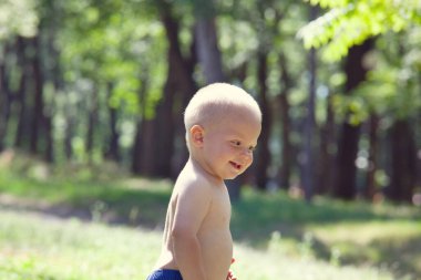 Küçük çocuk yaz parkında ilk adımlarını atıyor.