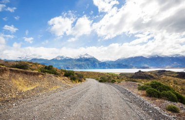 Güney Arjantin 'deki Patagonya manzaraları. Çayırda çakıl yolu gün batımında.