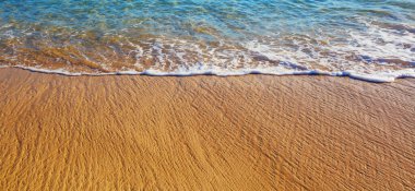 Kumsalda mavi dalga. Bulanık arkaplan ve güneş ışığı lekeleri. Dramatik doğal arka plan.