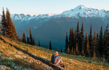 Gün doğumunda dağlarda dinlenen adam