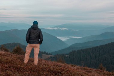 Gün doğumunda dağlarda dinlenen adam
