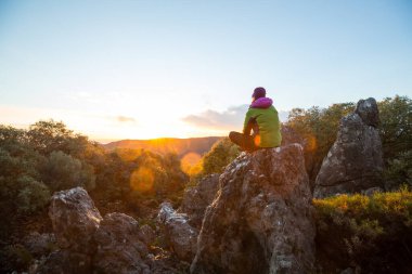 Gün doğumunda dağlarda dinlenen adam