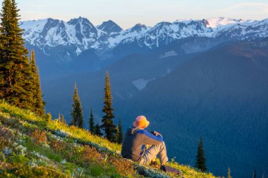 Gün doğumunda dağlarda dinlenen adam
