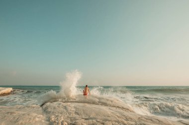 Deniz sahilinde dalgalarda oynayan genç bir kadın.