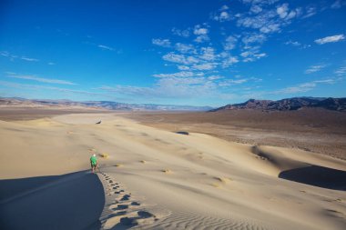 Kum çölünde bir yürüyüşçü. Gün doğumu zamanı.