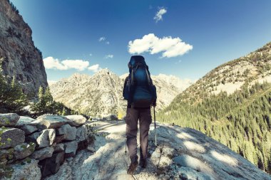 bir dağın tepesinde uzun yürüyüşe çıkan kimse