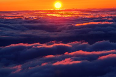 Bulutların üstünde tepe üzerinde günbatımı