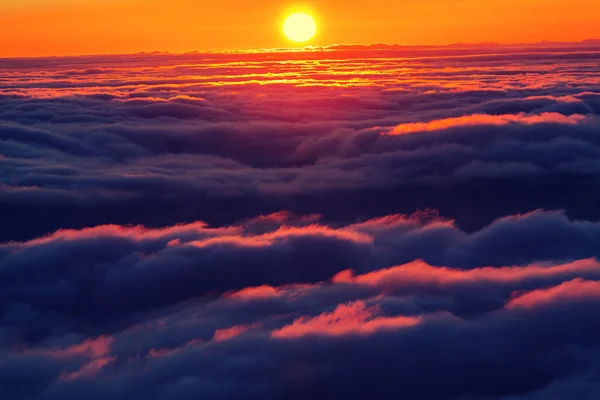 Zonsondergang op de heuvel boven de wolken — Stockfoto