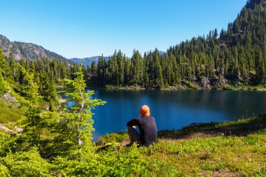 Dağlar göl kenarında oturan adam