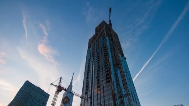 Sunset timelapse av skyscrapper konstruktion fungerar, zooma in — Stockvideo