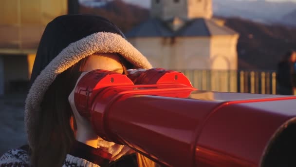 Турист, який дивиться на місто за допомогою біноклів, керованих монетою на заході сонця, жорсткий постріл — стокове відео