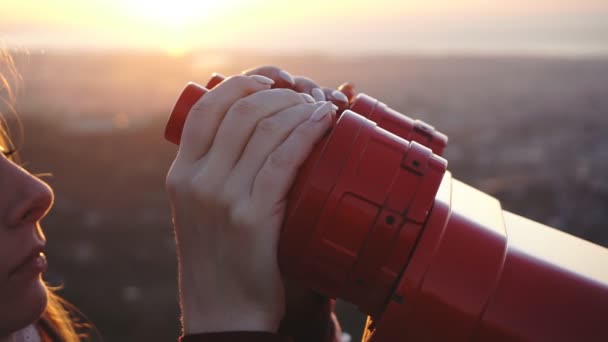 旅游在日落时分，特写侧面通过投币式双筒望远镜看市 — 图库视频影像