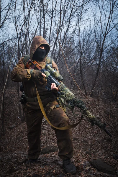 Sniper bär kamouflage kostym med gevär promenad i skogen — Stockfoto