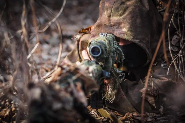 Sniper wearing camouflage suit with rifle hide in the woods — Stock Photo, Image