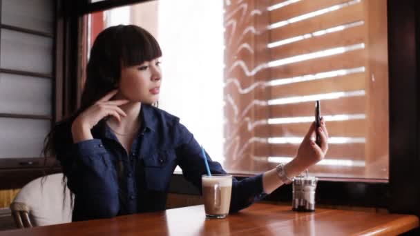 Chica joven haciendo selfie en el teléfono inteligente en el café — Vídeo de stock