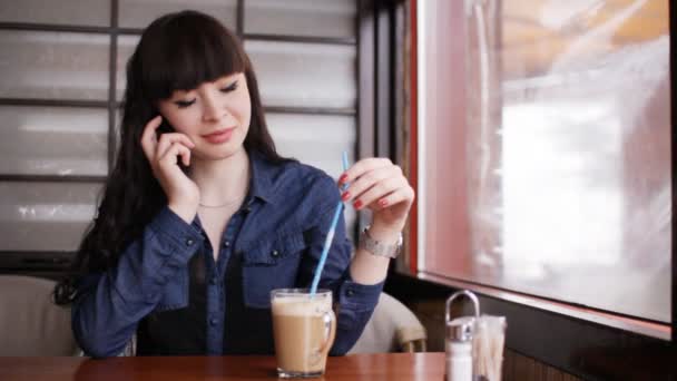 Chica joven hablando en el teléfono inteligente en la cafetería — Vídeos de Stock