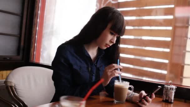 Young girl using smartphone in the cafe. Handheld. — Stock Video
