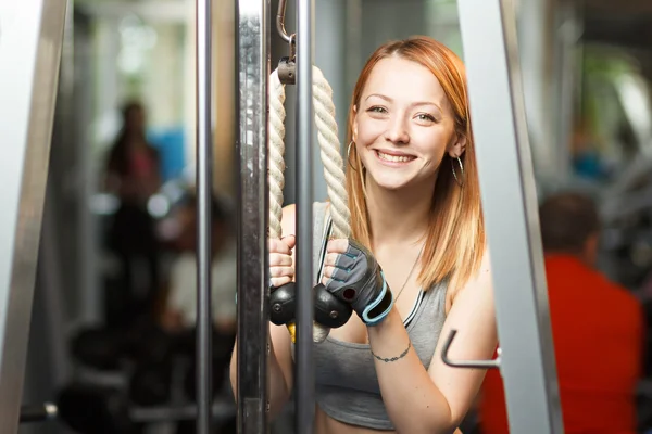 Chica fuerte joven hacer ejercicios en la máquina de cruce de cable —  Fotos de Stock