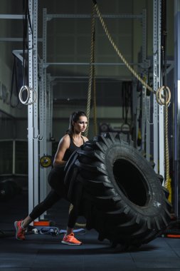 Güçlü kaslı kadın Crossfit eğitmen spor salonunda lastik egzersiz yapıyor