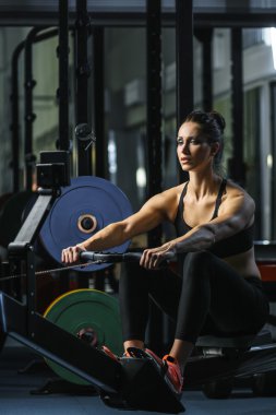 çekici kaslı kadın Crossfit eğitmen kapalı kürekçi üzerinde egzersiz yapmak
