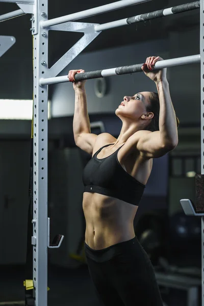 Poderoso atraente mulher CrossFit treinador fazer pull ups durante o treino — Fotografia de Stock