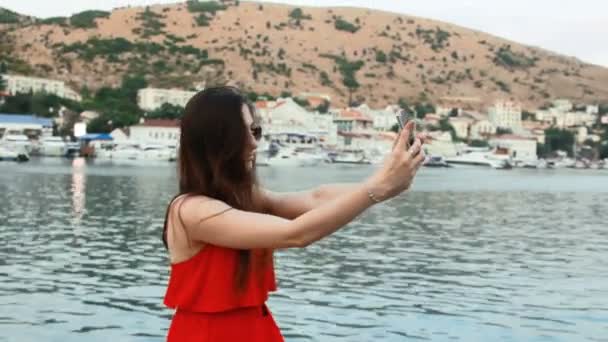 Chica sonriente tomando fotos con la cámara del teléfono inteligente al aire libre — Vídeos de Stock