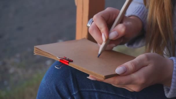 Reizen: mooi meisje toerist tekening zonsondergang op het strand. Close-up shot, Slow-Motion 60fps, handheld. — Stockvideo