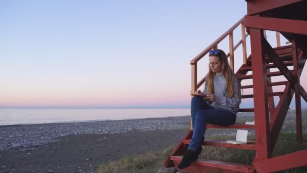 Viaggio: bella ragazza turista disegno tramonto in spiaggia. Colpo largo, rallentatore 60fps, statico . — Video Stock