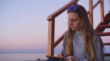 Seyahat: plajda gün batımı çizim güzel kız turist. Orta çekim, yavaş çekim, el.