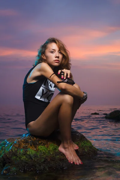 十几岁的女孩坐在石头上时装拍摄日落海滩 — 图库照片
