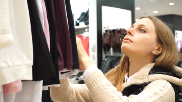 Shopping kvinna. Shopper tittar på kläder i kläder butik. Närbild varm, handhållna, ultrarapid 60fps. — Stockvideo