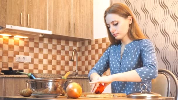 Estilo de vida de comida saudável: bela mulher casualmente cozinhando, cortando verduras na cozinha. Medium shot, handheld, câmera lenta 60 fps . — Vídeo de Stock