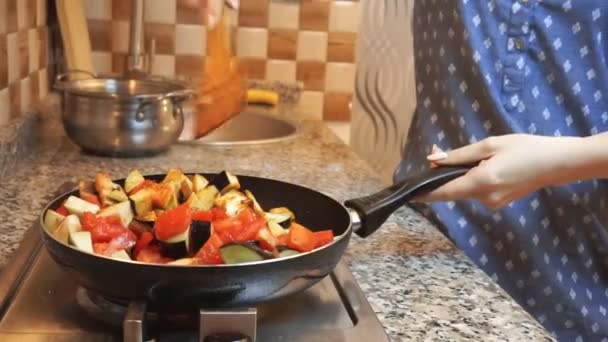 Gezonde levensstijl: mooie vrouw die terloops kookt, roer, plant groente in de pan in de keuken. Close-up opname, handheld. — Stockvideo