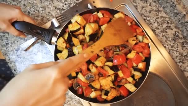 Estilo de vida saludable: hermosa mujer casualmente cocinar, remover, hervir verduras a fuego lento en la cacerola en la cocina. De arriba hacia abajo tiro, de mano . — Vídeo de stock