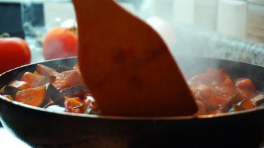 Sağlıklı gıda yaşam tarzı: güzel kadın rahat yemek, karıştırın, mutfakta tavada sebze kaynatın. Yakın çekim, statik, yavaş çekim 60 fps.