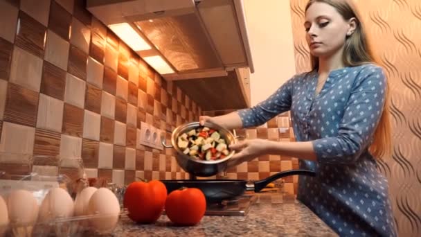 Estilo de vida de comida são: bela mulher casualmente cozinhando, pondo verduras na panela de ato de fritar na cozinha. Amplo tiro, de mão . — Vídeo de Stock