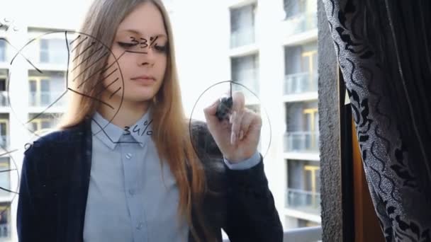 Mode de vie : belle jeune femme dessinant des graphiques d'entreprise de mathématiques sur le verre avec gratte-ciel en arrière-plan. Southpaw. Plan moyen, à la main, au ralenti 60 ips .