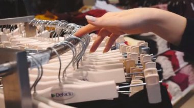 Alışveriş kadın. Alışveriş giyim mağazası giysilerle bakarak elleri. Atış, el, yakın çekim yavaş hareket 60fps.