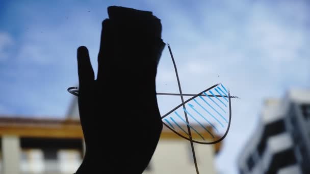 Estilo de vida: hermosa mujer joven limpiando gráficos de negocios de matemáticas del vidrio con cielo azul, rascacielos en el fondo. Silueta. Primer plano, de mano, cámara lenta 60 fps . — Vídeo de stock