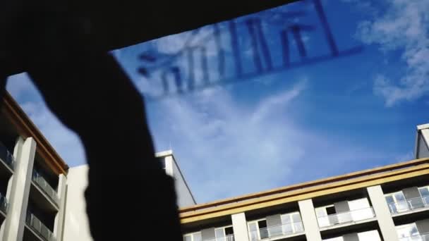 Lifestyle: beautiful young woman cleaning math business graphs from the glass with blue sky, skyscraper on background. Silhouette. Close-up shot, handheld, slow motion 60 fps. — Stock Video