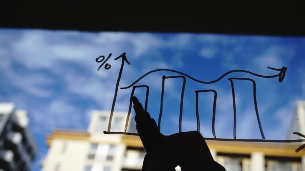 Stile di vita: bella giovane donna che disegna grafici aziendali matematici sul vetro con cielo blu, grattacielo sullo sfondo. Silhouette. Zampa sinistra. Primo piano, palmare, rallentatore 60 fps . — Video Stock