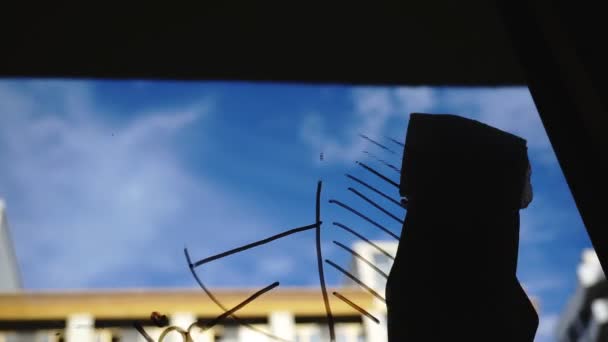 Stile di vita: bella giovane donna pulizia grafici aziendali di matematica dal vetro con cielo blu, grattacielo sullo sfondo. Silhouette. Colpo ravvicinato, palmare . — Video Stock