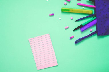 Kalemler, kalemler, haplar, tabletler ve boş kopya alanı olan parlak yeşil arkaplan üzerindeki not defterleriyle dolu renkli şehir fotoğrafı