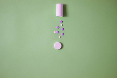 Açık şişenin modern minimalist fotoğrafı, mor ve beyaz tabletler parlak yeşil arka planda fotokopi alanı ile