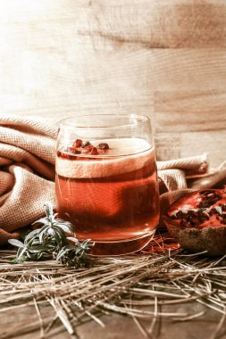 Baharatlı bir bardak şarap ve ahşap masada otlar.