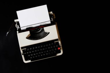 Siyah zemin üzerinde boş kağıt olan daktilo