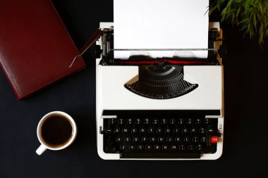 Dizüstü bilgisayarı ve kahvesi olan bir daktilo.