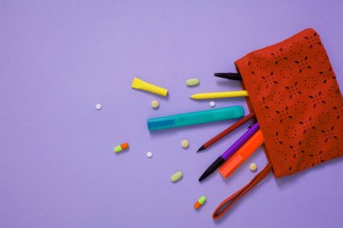 Renkli arkaplan üzerindeki renkli kalemlerin ve kırtasiyelerin üst görünümü